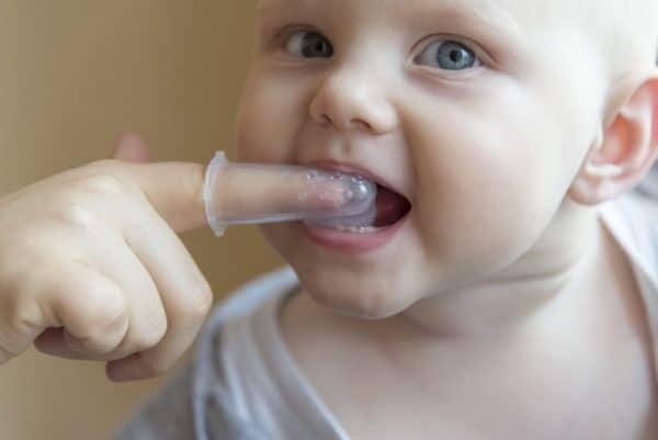 Mom prepares baby for first dental visit by cleaning teeth.